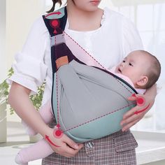 a woman is holding a baby in a sling that's attached to her chest