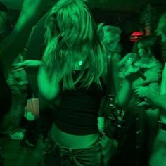 a group of people standing around in a room with green light on the walls and floor