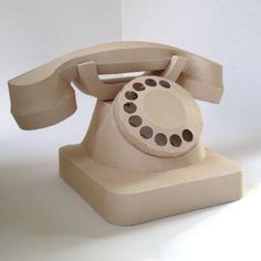 an old - fashioned phone is sitting on a white surface and it appears to be made out of clay