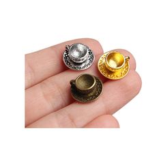 three miniature teapots are sitting on someone's finger, one is gold and the other is silver