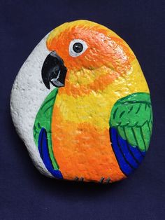 an orange and green parrot painted on a rock