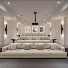 a large white couch sitting in the middle of a living room next to two framed pictures