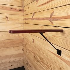 a wooden room with wood walls and a shelf hanging from the wall, along with a metal hook