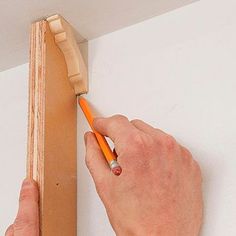 a man is using a pencil to draw on the side of a piece of wood