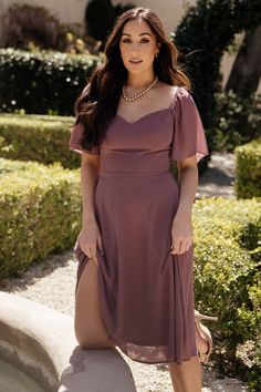 a woman in a purple dress posing for the camera