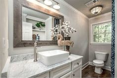 a bathroom with a sink, mirror and toilet in it's centerpieces