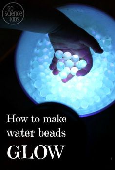 a person holding their hand over a bowl filled with water beads that glow in the dark