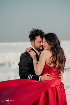 a man and woman embracing each other in front of snow covered ground with ice behind them