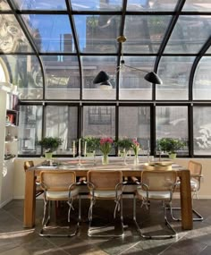 a dining room table and chairs in front of large windows