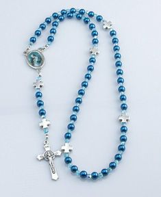 "Handmade in the USA this charming rosary was made using 6mm dark blue pearl beads with Czech fire-polished AB Aquamarine glass accent beads and features metal \"Our Father crosses, Rosa Mystica pictured on the rosary centerpiece and a Benedictine crucifix. You can customize it with a choice of five different rosary centerpieces. This affordable Catholic gift is perfect for Baptism, First Communion, Confirmation, RCIA Candidates, or for anyone who would like a lightweight rosary. It comes in a d Blue Beaded Rosary As A Gift, Adjustable Blue Rosary With 8mm Beads, Blue Rosary With Round Beads For Gift, Blue Rosary With 8mm Beads And Crucifix, Blue Rosary With 8mm Beads In Cross Shape, Blue Rosary Bracelet For Jewelry Making, Blue Cross Rosary For Gift, Blue Cross Rosary As Gift, Blue Cross Jewelry With 8mm Beads