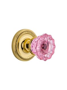 a pink and gold door handle on a white wall with a circular rosette knob