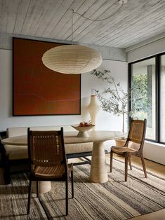 a dining room with chairs and a large painting on the wall above it's table