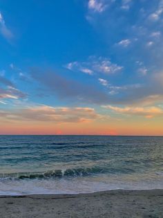 the sun is setting over the ocean with clouds in the sky