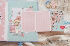 an open scrapbook with pink and blue pages on top of it, surrounded by flowers