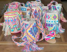 several colorful bags with tassels and sandals on a wooden table next to each other