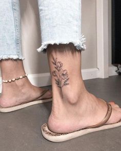 a woman's foot with a small flower tattoo on her left ankle and the bottom part of her leg