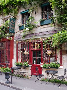 an outdoor cafe with tables and chairs on the side of the street in front of it