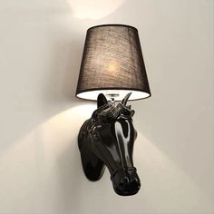 a black horse head mounted to the side of a wall with a lamp on it