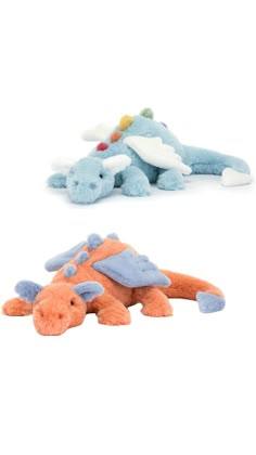 two stuffed animals sitting next to each other on top of a white surface and one is blue, the other has an orange dragon