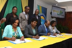 a group of people sitting at a table signing papers