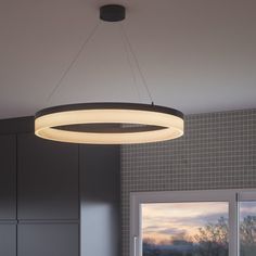 a large circular light fixture hanging from the ceiling in a kitchen with grey walls and cabinets