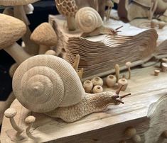 a close up of a wooden carving of snails on a piece of wood with mushrooms in the background