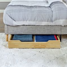 a bed with two drawers underneath it on the floor in front of a white rug