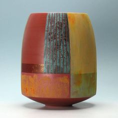 a close up of a vase on a white surface with red, yellow and green stripes