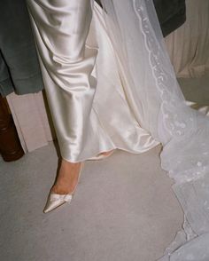 a bride and groom standing next to each other in their wedding gowns, holding hands