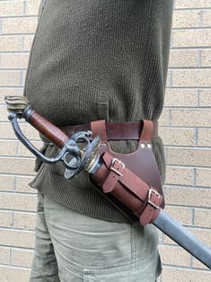 a person holding a large metal and leather tool belt with a long blade attached to it