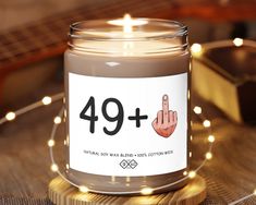 a candle with a sign that says 39 plus on it and lights around the jar