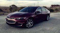 a maroon car is parked on the gravel