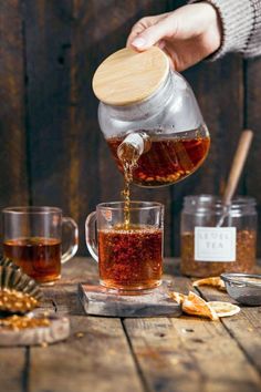 a person pouring tea into a glass mug