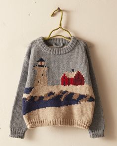 a sweater hanging up on a wall next to a hanger with an image of a boat