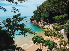 the beach is surrounded by trees and rocks