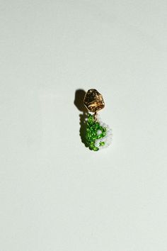 a small piece of jewelry sitting on top of a white table next to a green object