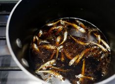 fish are being cooked in a pot on the stove