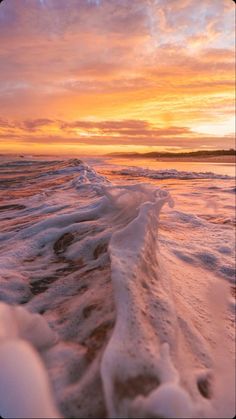 the beach is covered in ice as the sun sets