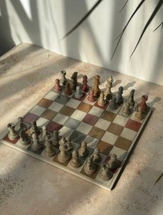 a chess board with several pieces on it and shadow from the wall in the background