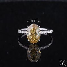 a fancy yellow diamond ring with diamonds on the sides and an oval shaped center stone