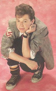 a young man in a suit and tie posing for a photo with his hand on his chin