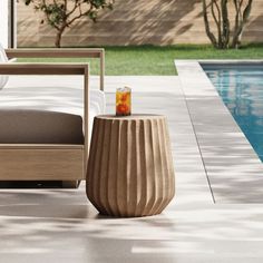 an outdoor lounge chair next to a pool with a drink on the table in front of it