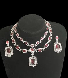 Enhance your elegance and add a touch of sparkle to your ensemble with this stunning Silver Finish, and ruby red (hot pink)American Diamond double layer Neck Line accompanied by matching Dangle Earrings. The necklace features a captivating silver finish that exudes sophistication, while the vibrant red American diamonds and shimmering diamonds create a mesmerizing focal point. Each carefully crafted stone is expertly placed to maximize brilliance and create a dazzling effect. The necklace line s Elegant Ruby Jewelry Sets For Party, Ruby Necklace For Party, Fine Jewelry, Dazzling Ruby Necklace For Party, Luxury Red Bridal Necklace For Celebration, Hand Set Ruby Jewelry Sets For Party, Dazzling Ruby Bridal Necklace For Parties, Luxury Red Jewelry Sets For Wedding, Exquisite Red Bridal Necklace For Celebrations, Dazzling Ruby Necklace For Celebration