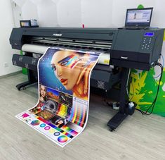 an image of a large printer in front of a wall with colorful images on it