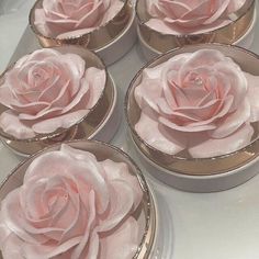 six pink roses are sitting in tins on the counter top, ready to be decorated