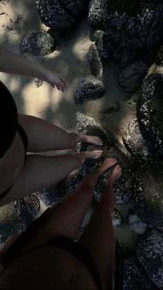 two people standing in the sand near rocks