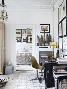 a living room filled with lots of furniture and pictures on the wall next to a desk