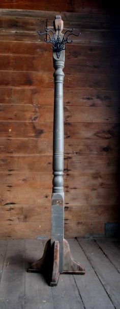 an old fashioned metal pole with a candle holder on it's base in front of a wood paneled wall