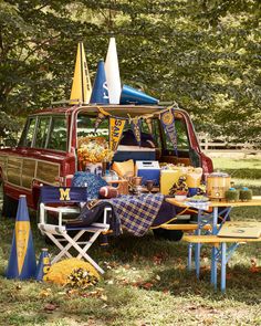 an old car with decorations on the roof is parked in front of a picnic table