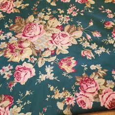 a floral print fabric with pink and blue flowers on green background, close up view